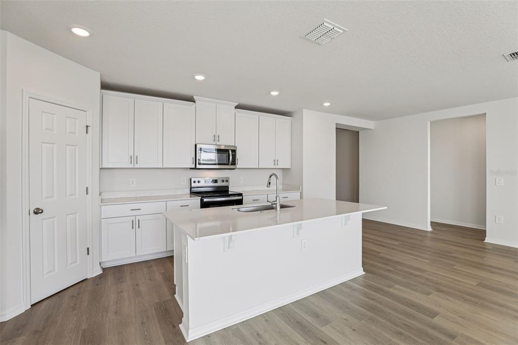 4018 Copperleaf Lane Kissimmee, FL 34759 - Photo 13 of 36 a large kitchen with cabinets and wooden floor