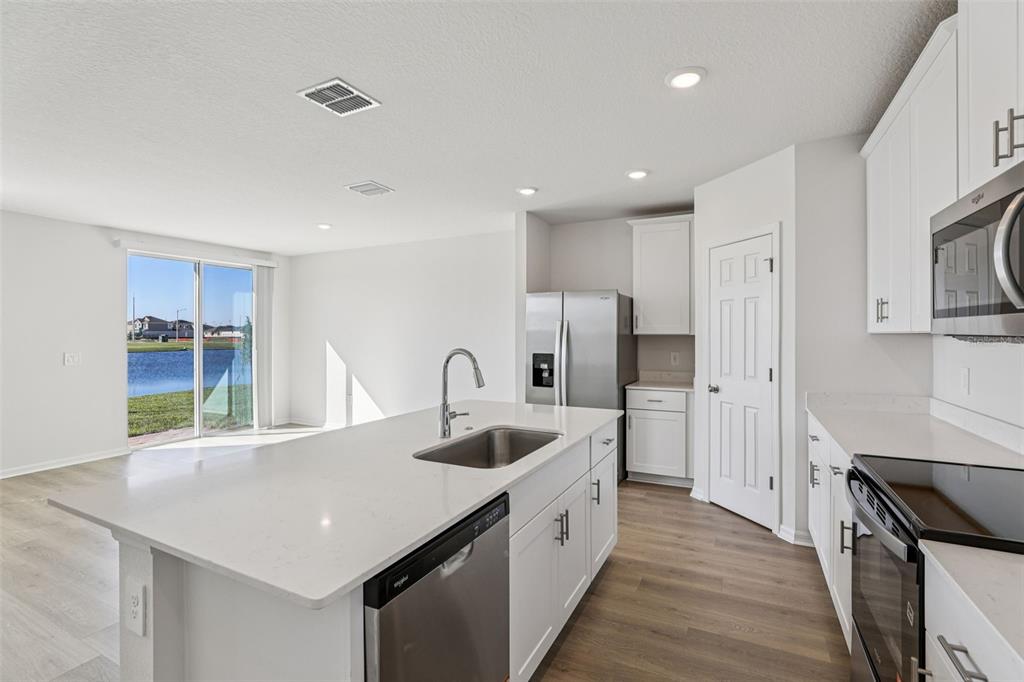4018 Copperleaf Lane Kissimmee, FL 34759 - Photo 14 of 36 a kitchen with stainless steel appliances granite countertop a sink dishwasher a refrigerator and a stove with wooden floor