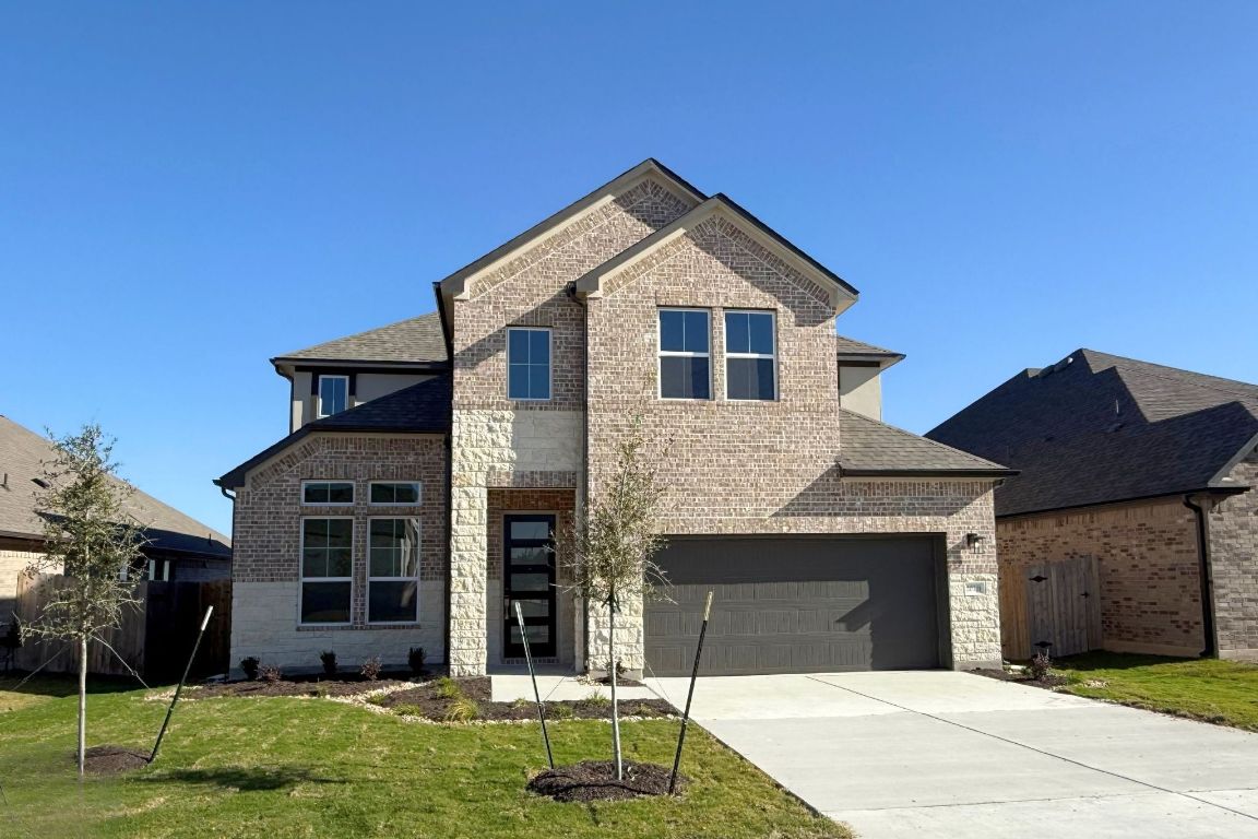 View of front of house featuring brick siding, driveway, an attached garage, and a shingled roof