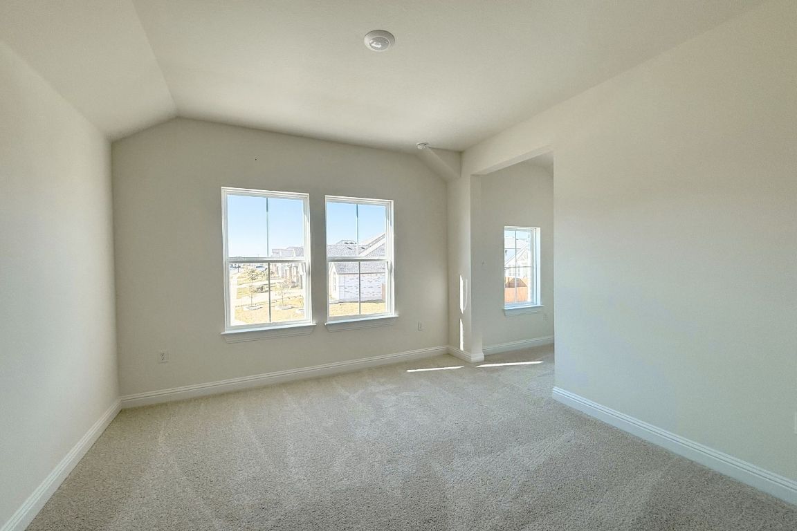 20301 Dustin Lane Pflugerville, TX 78660 - Photo 15 of 30 Empty room with light colored carpet and vaulted ceiling