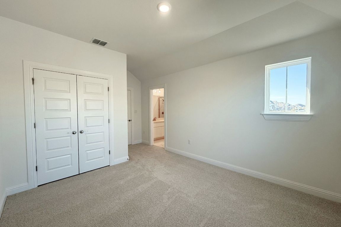 20301 Dustin Lane Pflugerville, TX 78660 - Photo 19 of 30 Unfurnished bedroom featuring carpet flooring, a closet, ensuite bathroom, and lofted ceiling