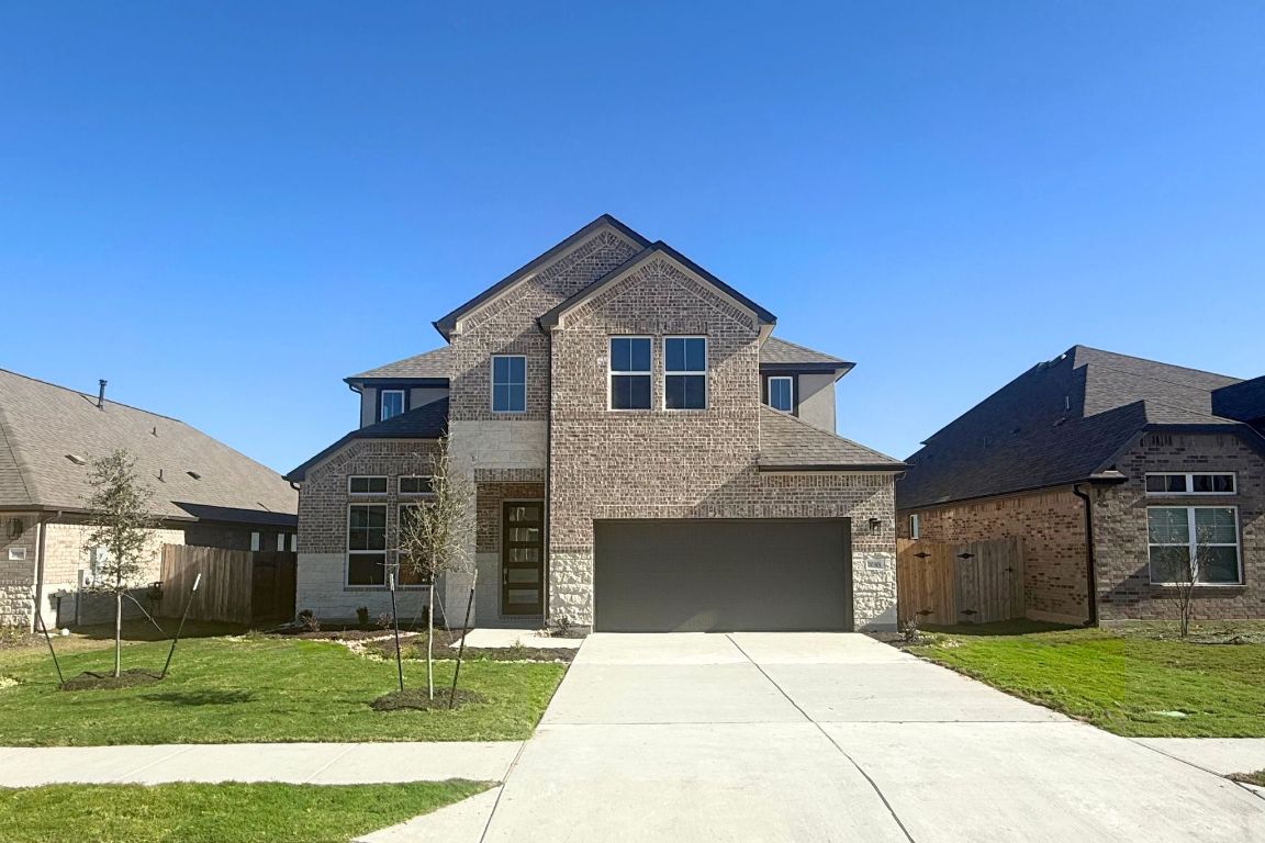 20301 Dustin Lane Pflugerville, TX 78660 - Photo 2 of 30 View of front of property featuring brick siding, driveway, and an attached garage