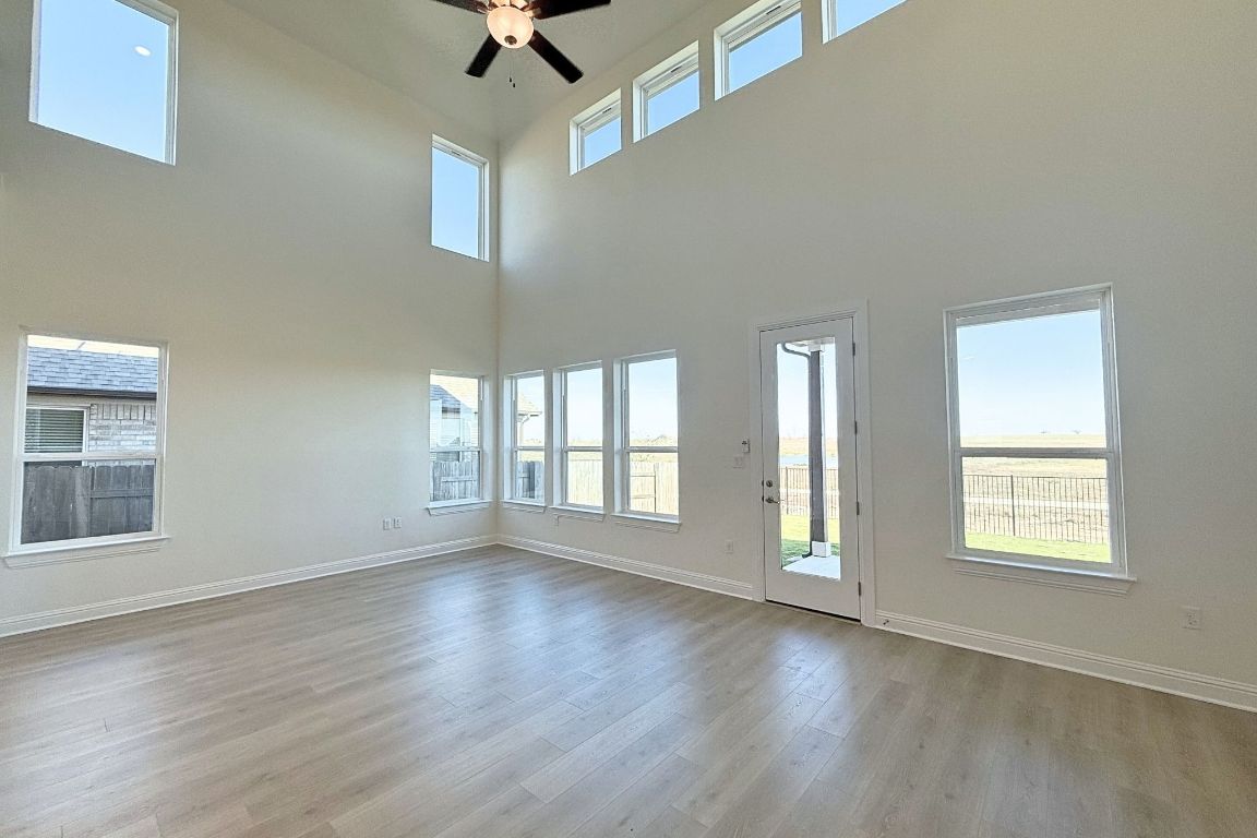 20301 Dustin Lane Pflugerville, TX 78660 - Photo 4 of 30 Spare room with light wood finished floors, plenty of natural light, ceiling fan, and a towering ceiling