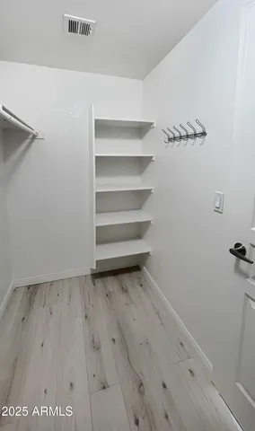 an empty room with chandelier fan and windows