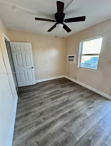 a view of an empty room with a window and wooden floor