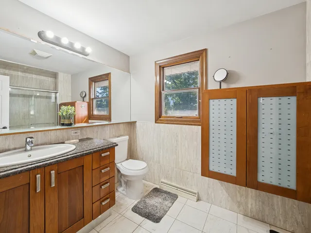 a spacious bathroom with a granite countertop sink toilet and mirror
