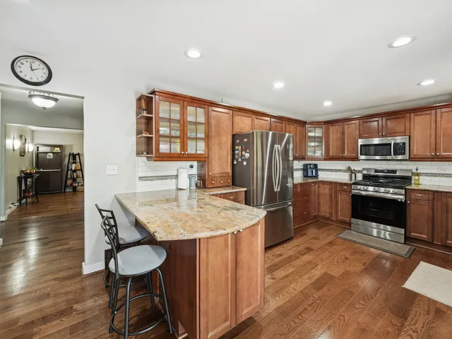 a kitchen with stainless steel appliances granite countertop a stove refrigerator and a wooden cabinets