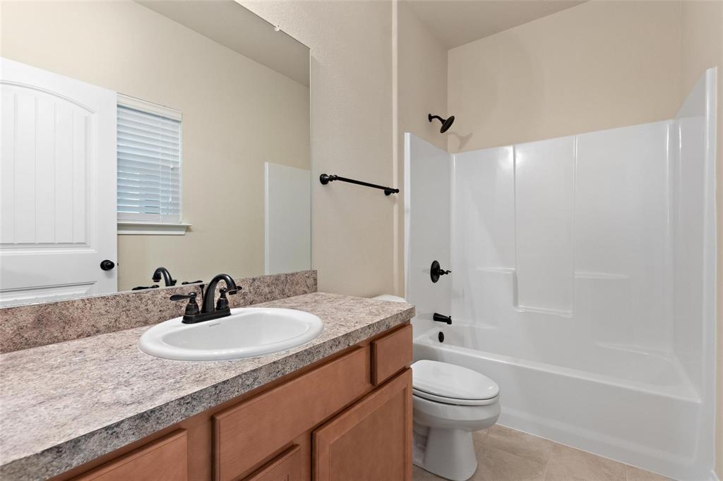1119 East Epstein Street Sherman, TX 75090 - Photo 10 of 13 a bathroom with a granite countertop sink toilet and shower