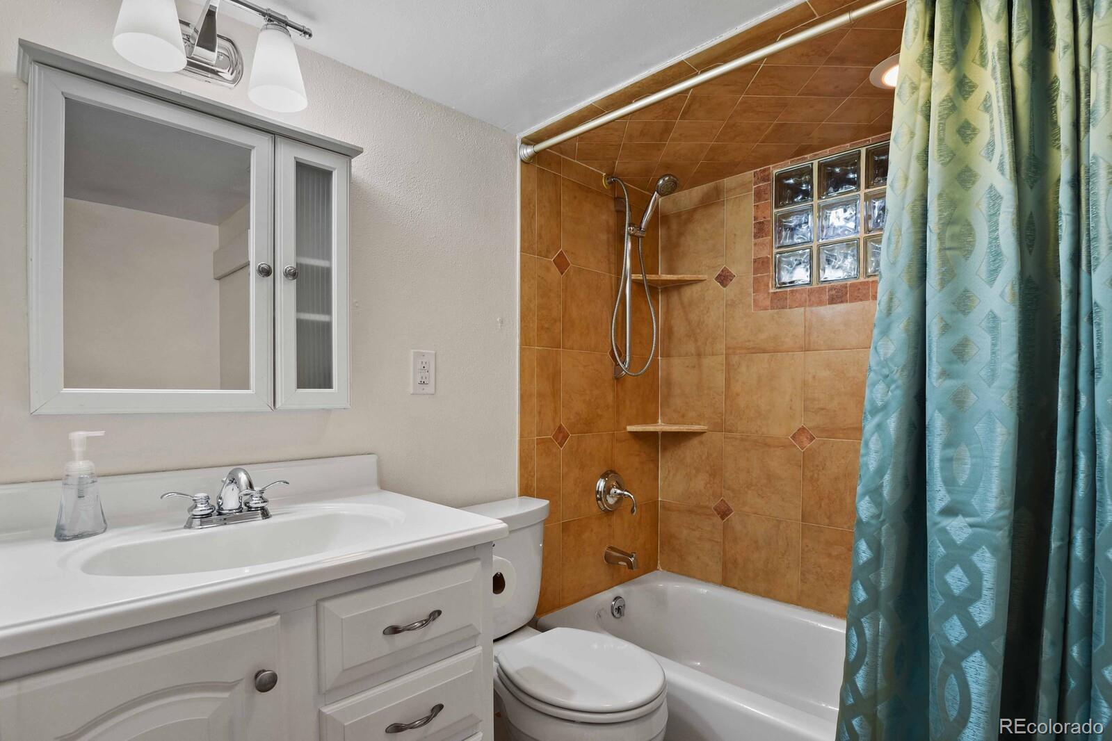 3615 Lowell Boulevard Denver, CO 80211 - Photo 15 of 23 a bathroom with a granite countertop sink toilet a mirror a vanity and shower