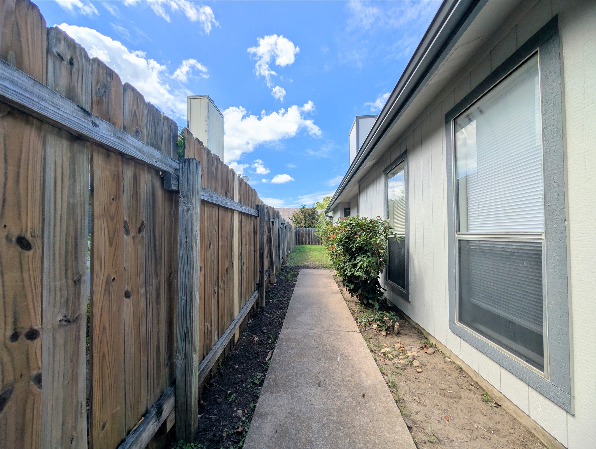 2036 Redwing Way Round Rock, TX 78664 - Photo 4 of 23 A private side yard path leads to the backyard, secured by a tall wooden fence.