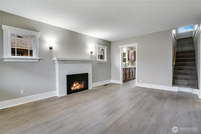 a view of an empty room with wooden floor fireplace and a window