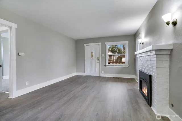 an empty room with windows a fireplace and wooden floor