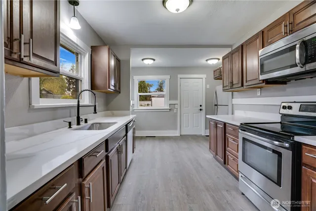 a kitchen with stainless steel appliances granite countertop a sink a stove and cabinets