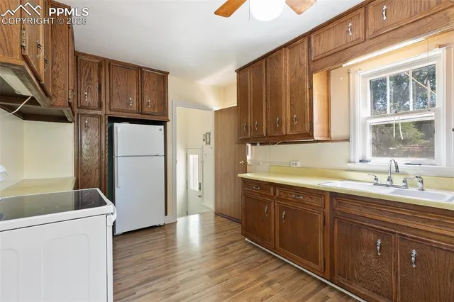 a kitchen with a sink a refrigerator and wooden cabinets