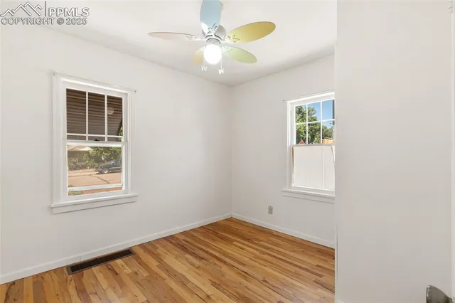 an empty room with windows and fan