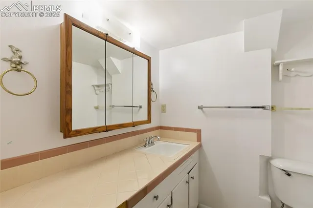 a bathroom with a granite countertop sink mirror vanity and toilet