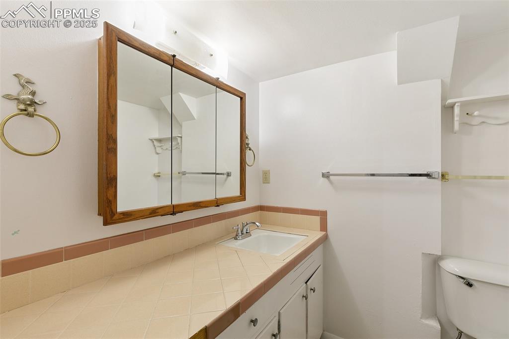 623 Swope Avenue Colorado Springs, CO 80909 - Photo 29 of 39 a bathroom with a granite countertop sink mirror vanity and toilet