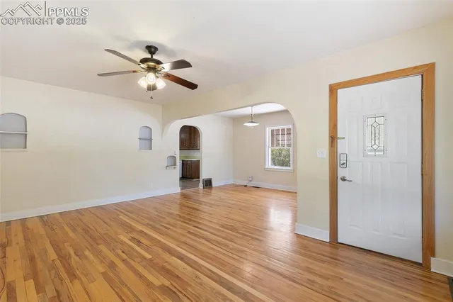a view of empty room with wooden floor and ceiling fan