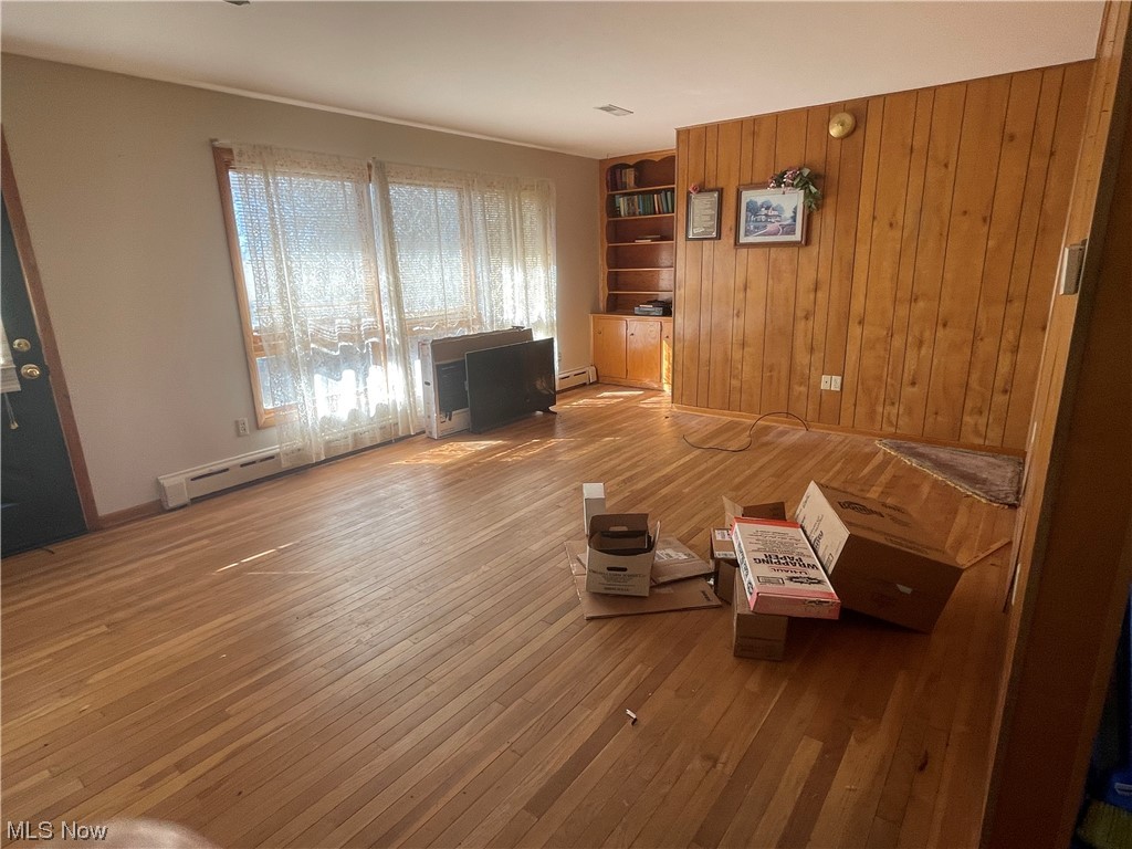 4010 Workman Road Mount Perry, OH 43760 - Photo 10 of 36 Unfurnished room featuring wood-type flooring, wood walls, and a baseboard heating unit