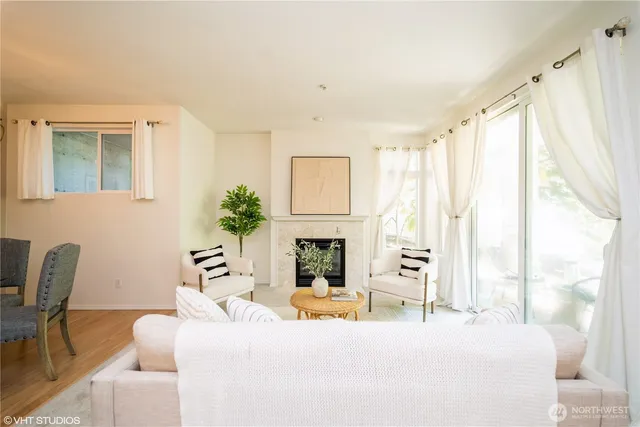 a living room with furniture a fireplace and a large window with garden view