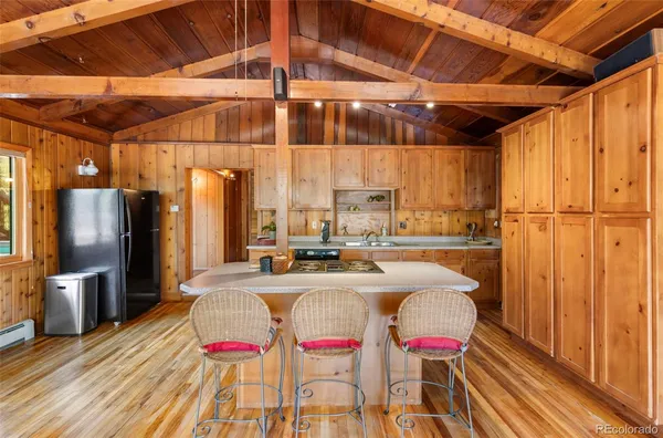 a kitchen with stainless steel appliances kitchen island granite countertop a table chairs and a refrigerator