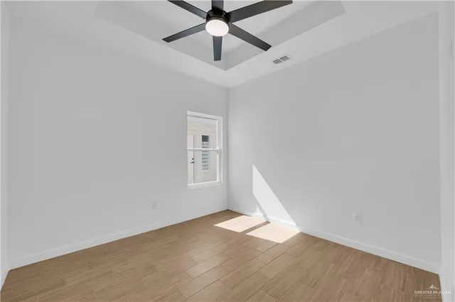 a view of empty room with wooden floor and fan