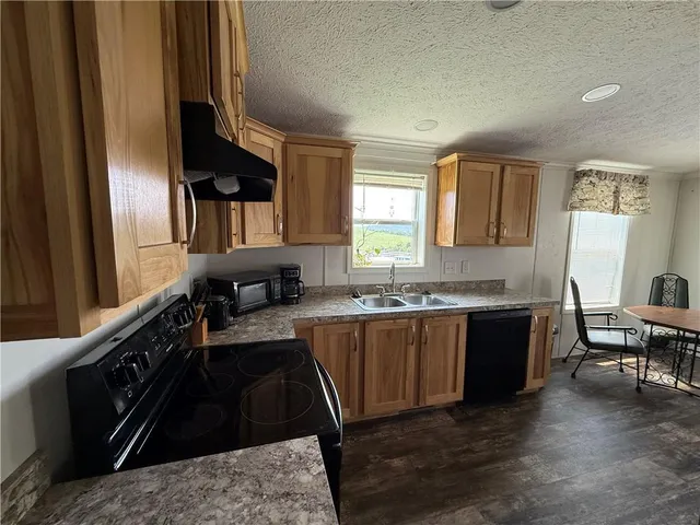 a large kitchen with granite countertop a sink and dishwasher a stove top oven with wooden floor