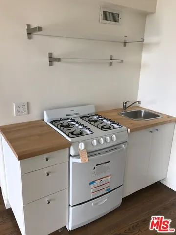 a kitchen with a stove and wooden floor