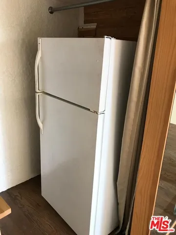 a white refrigerator freezer and a wooden floor