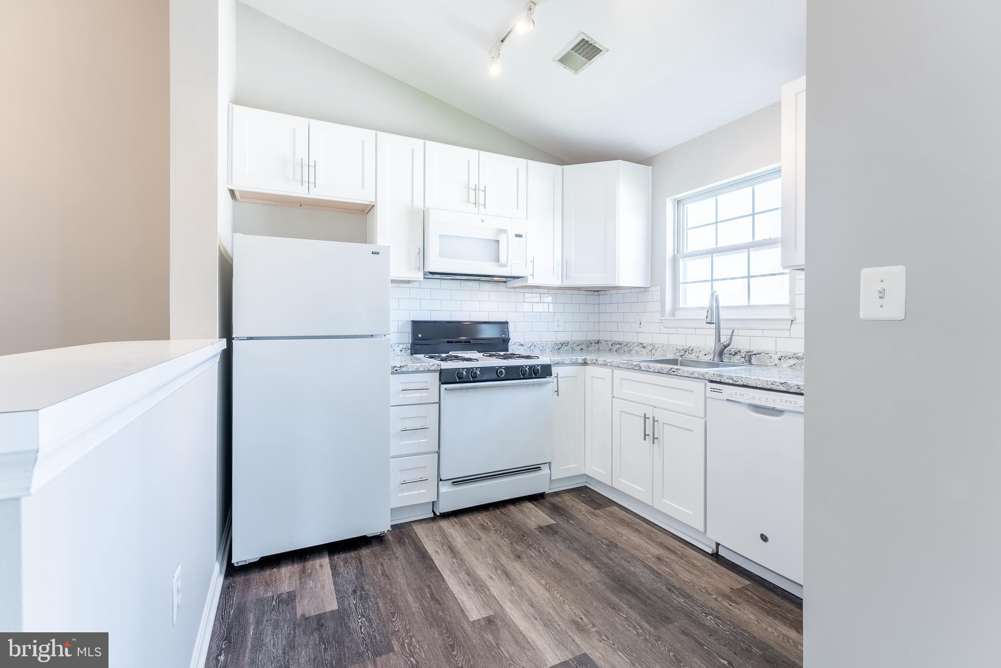 645 Constellation Square Southeast, Unit L Leesburg, VA 20175 - Photo 22 of 44 a kitchen with a refrigerator wooden floor and white cabinets