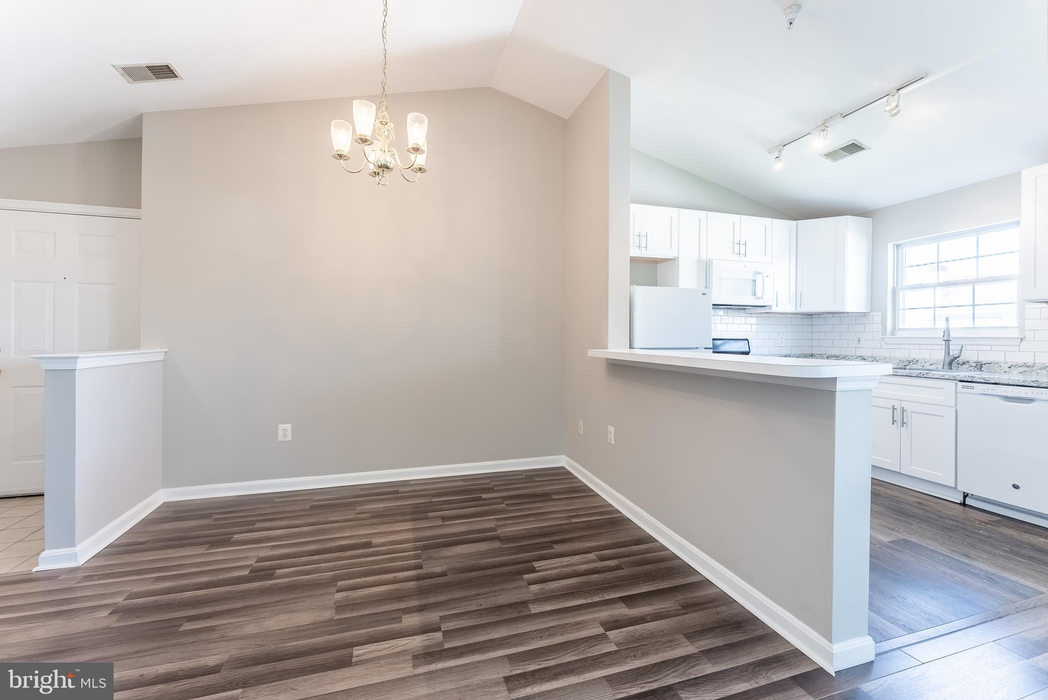 645 Constellation Square Southeast, Unit L Leesburg, VA 20175 - Photo 27 of 44 a kitchen with kitchen island a sink dishwasher a stove and white cabinets with wooden floor