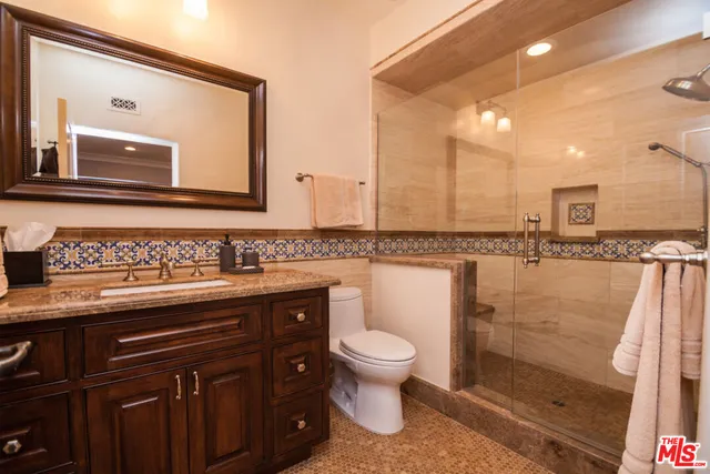 a bathroom with a granite countertop sink a toilet and a mirror