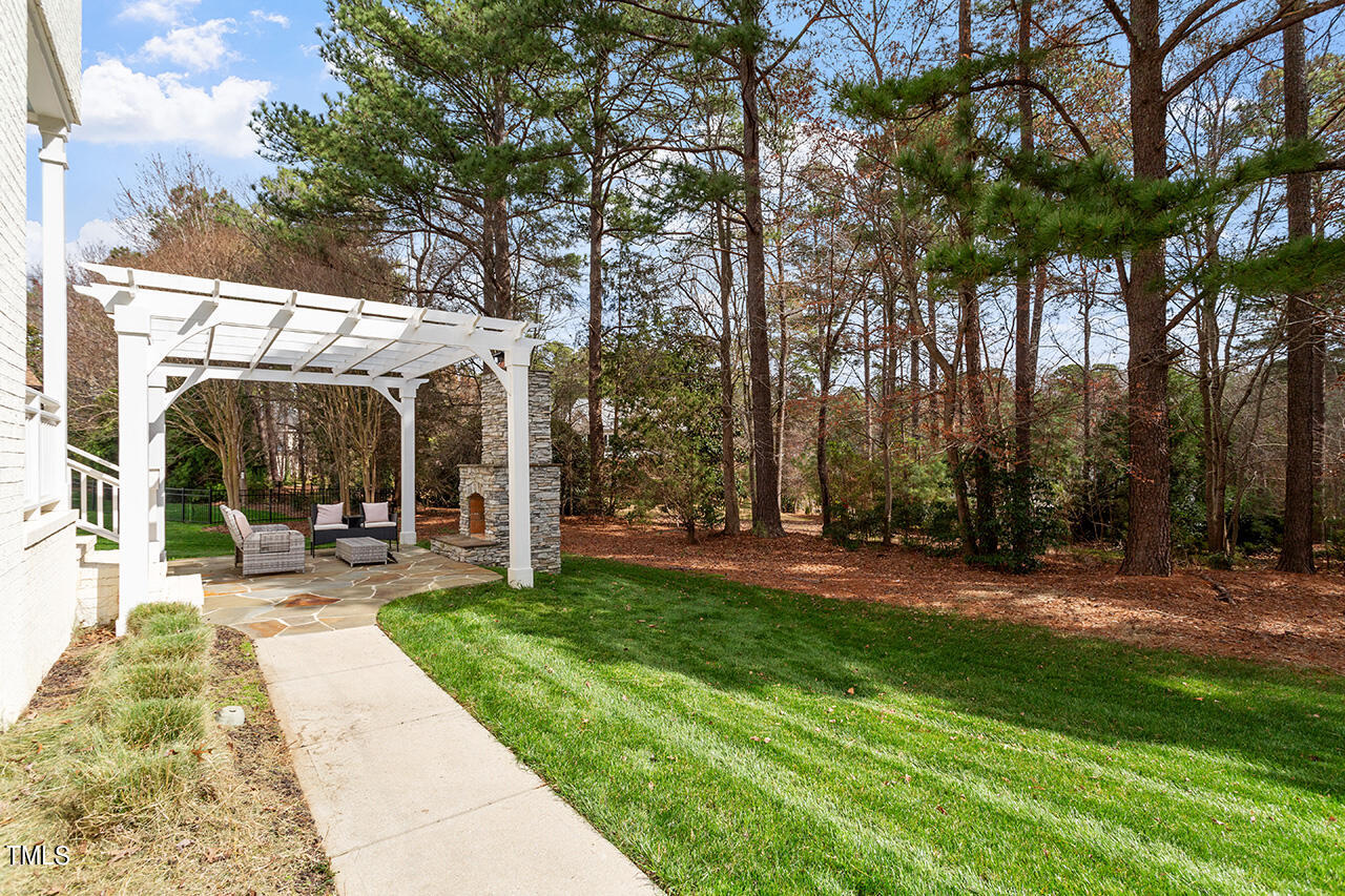 2000 Greyhawk Place Apex, NC 27539 - Photo 12 of 59 a view of a patio with table and chairs under an umbrella with large trees