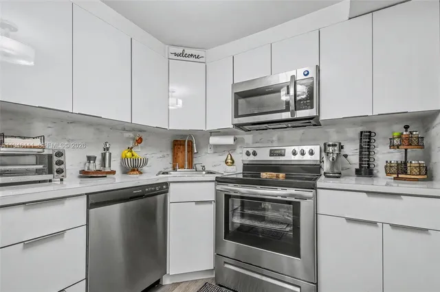 a kitchen with stainless steel appliances granite countertop grey cabinets a stove a sink and dishwasher