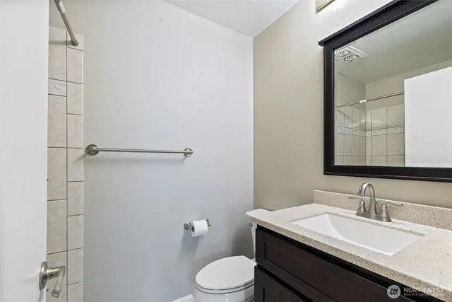 a bathroom with a granite countertop sink toilet a mirror and shower