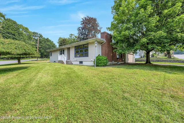 a view of a house with a big yard and large trees