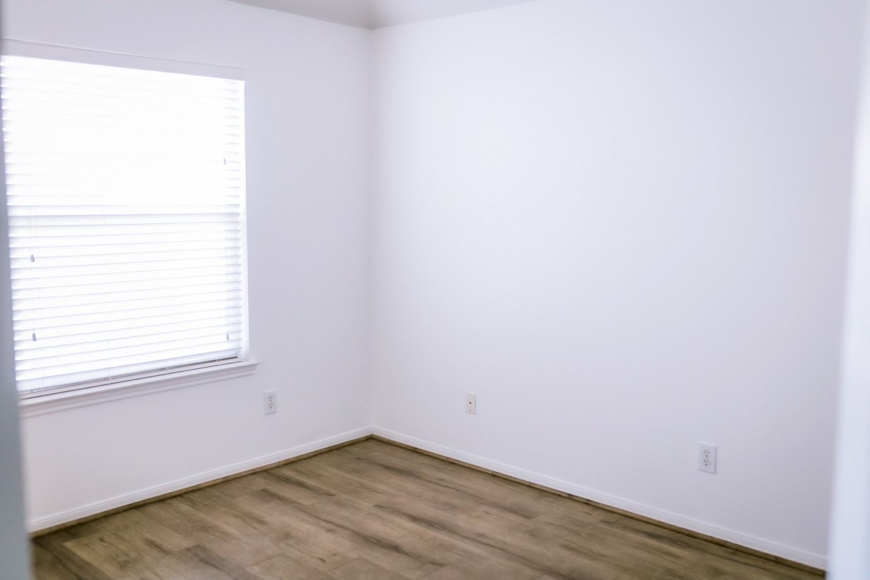22402 Rue Canyon Court Katy, TX 77450 - Photo 13 of 18 This light-filled bedroom is a blank canvas ready for your imagination. Boasting modern, neutral wood-look flooring and crisp white walls, it makes an ideal children's room, guest suite, or dedicated home office. A large, multi-pane window with blinds offers beautiful views of the neighborhood while keeping the space feeling open and airy.