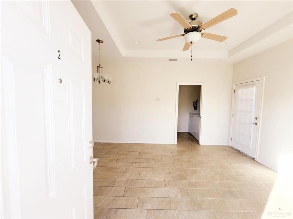 5601 Nightingale Avenue, Unit 2 McAllen, TX 78504 - Photo 9 of 12 Empty room featuring a tray ceiling, ceiling fan, and separate washer and dryer