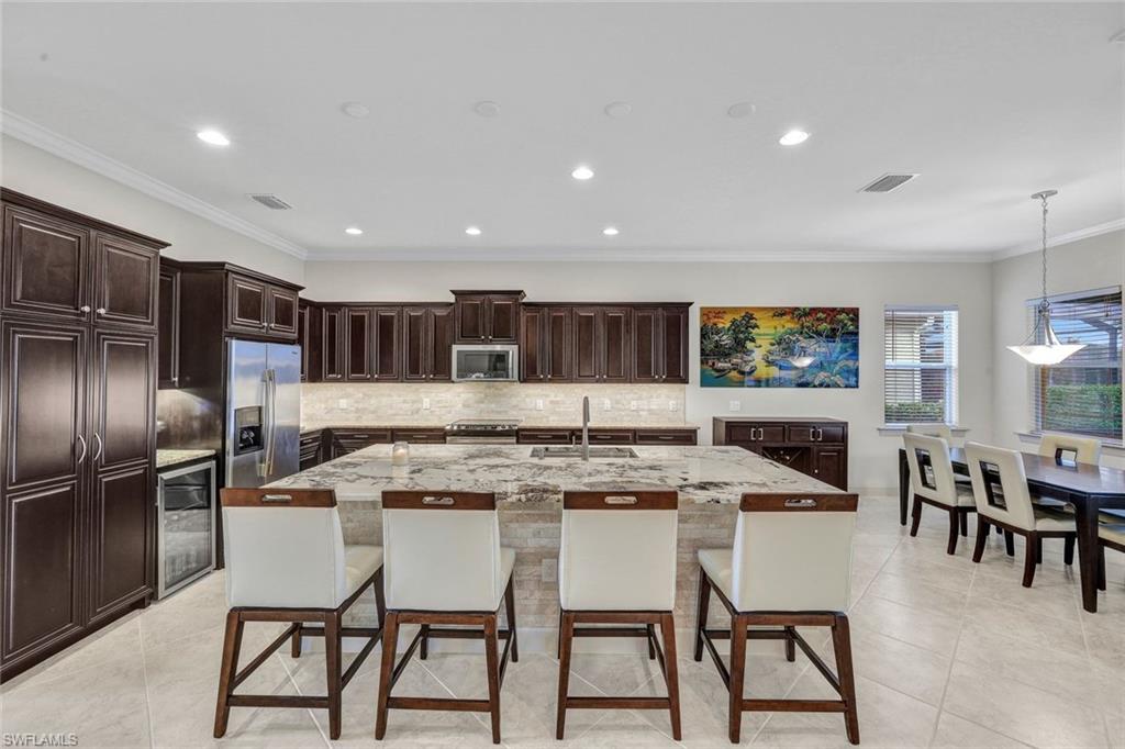 9111 Graphite Circle Naples, FL 34120 - Photo 5 of 33 a kitchen with stainless steel appliances kitchen island granite countertop a dining table chairs and a refrigerator
