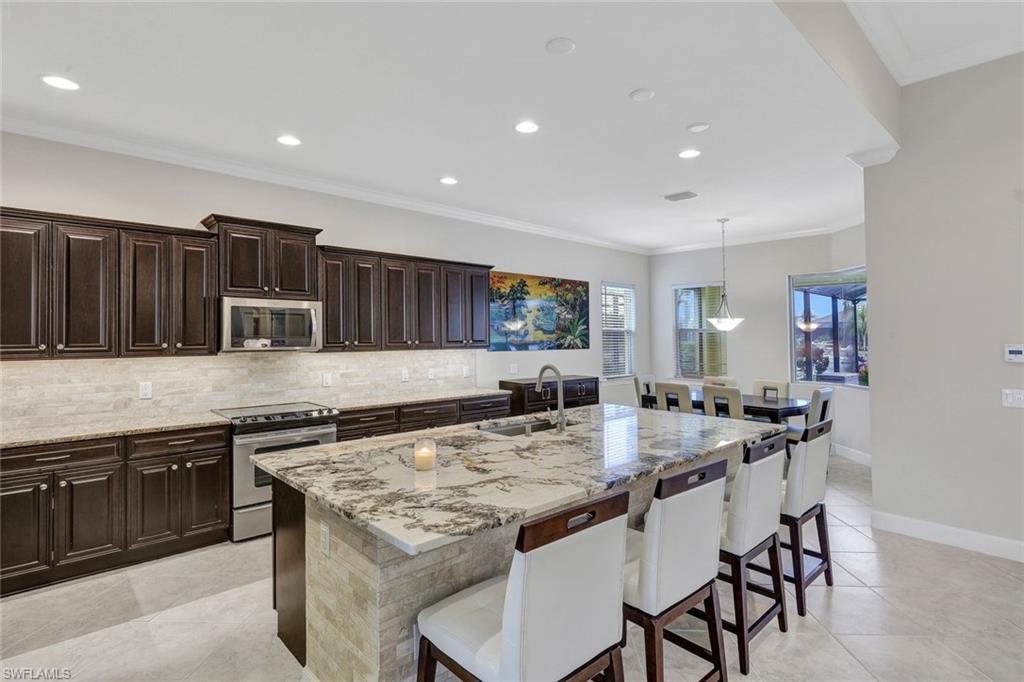 9111 Graphite Circle Naples, FL 34120 - Photo 6 of 33 a kitchen with stainless steel appliances granite countertop a stove top oven a sink and a refrigerator
