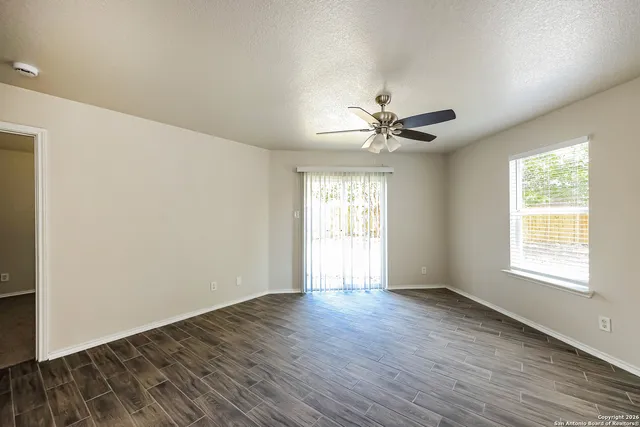 a view of an empty room with a window and a ceiling fan