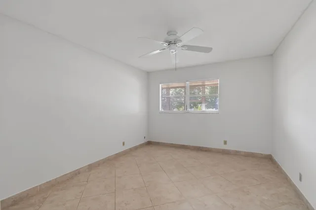 an empty room with a window and ceiling fan