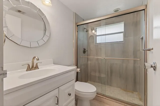 a bathroom with a sink a mirror a toilet and shower