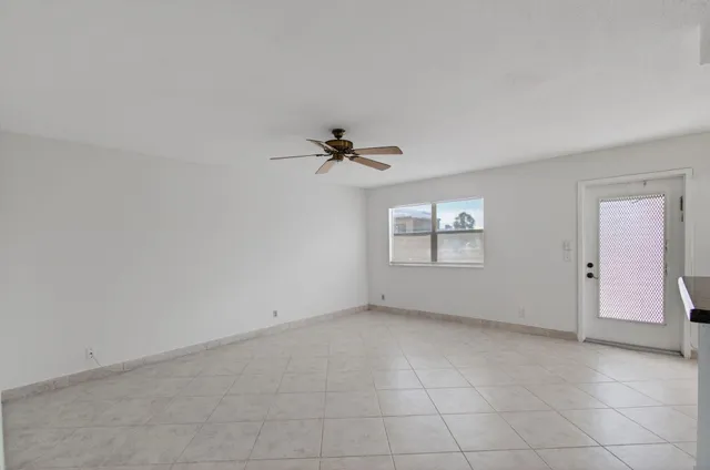 an empty room with a ceiling fan and a window