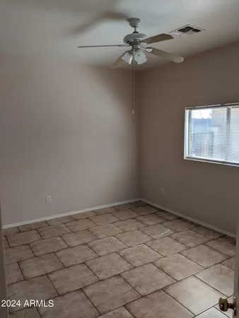 an empty room with windows and fan