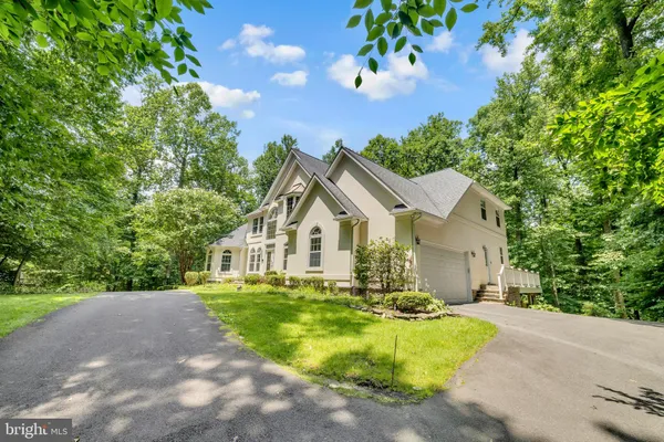 an aerial view of a house with a yard and a forest
