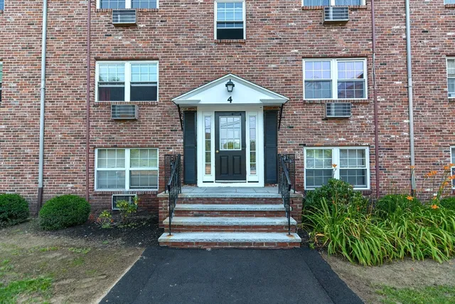 a front view of a house with a yard and potted plants