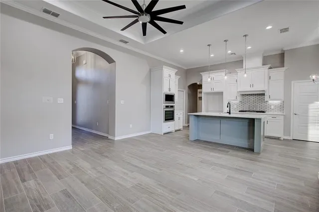 a large kitchen with stainless steel appliances kitchen island a large counter top and a wooden floors