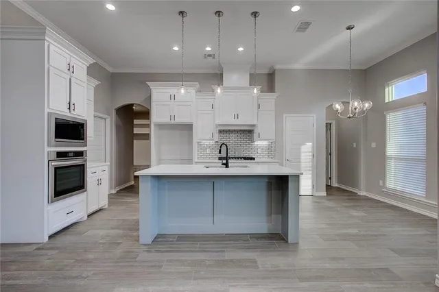 a large kitchen with stainless steel appliances a large counter top a sink and a refrigerator