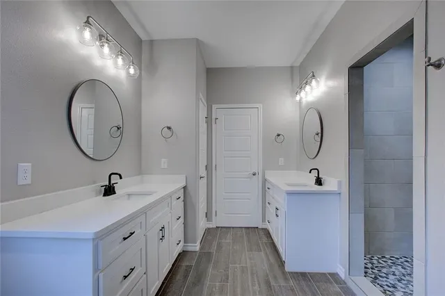 a spacious bathroom with a double vanity sink a mirror and shower